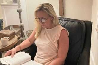 Marjorie Taylor Greene reading a Bible in a living room with crosses on the wall.