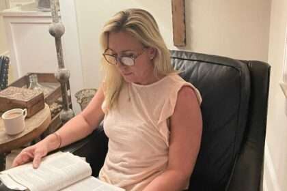Marjorie Taylor Greene reading a Bible in a living room with crosses on the wall.