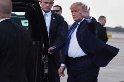 President Donald J. Trump waves while walking beside Secret Service agents.