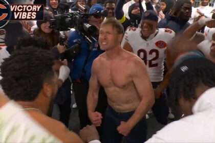 Chicago Bears head coach Ben Johnson celebrates shirtless in a crowded locker room after a win over the Philadelphia Eagles.