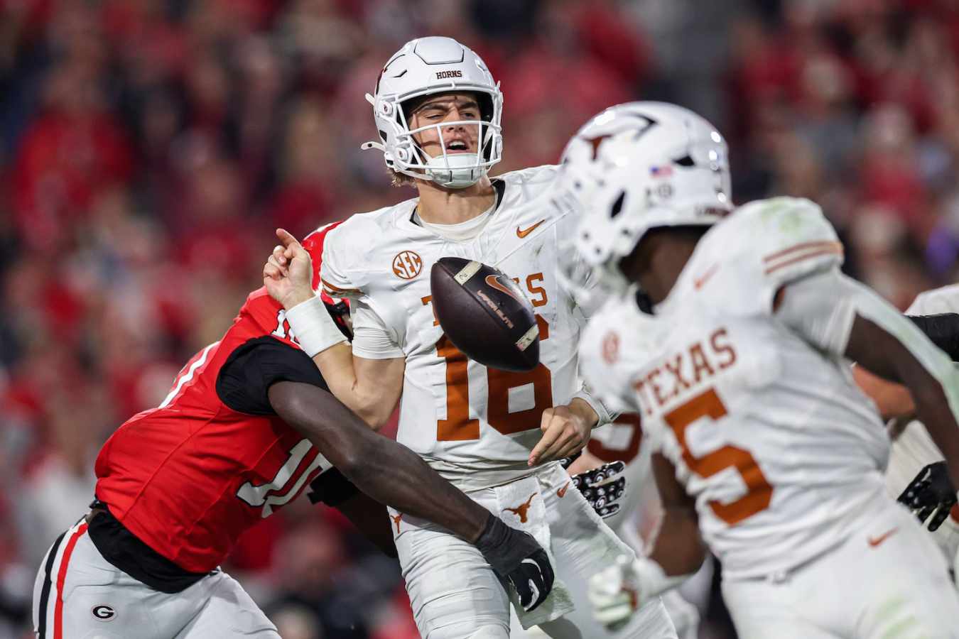 Texas quarterback Arch Manning is hit by a Georgia defender during a play, causing the ball to come loose.
