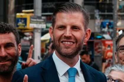 Eric Trump smiling at an outdoor public appearance.