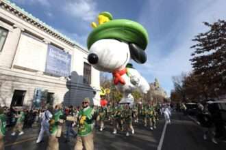 Parade staff guiding a large Snoopy balloon during the Macy’s Thanksgiving Day Parade.