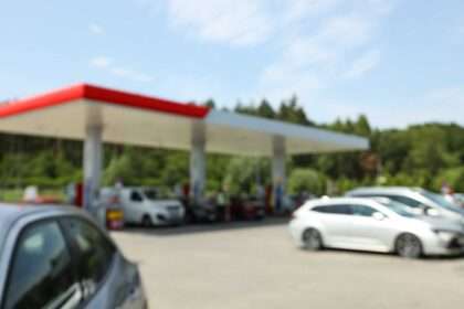 Gas station with multiple cars parked and fueling under a canopy.